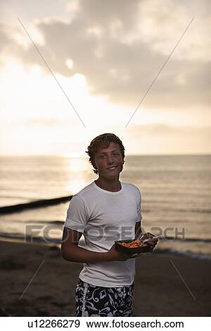 Teenage boy eating on beach View Large Photo Image Stock Photo - Teenage boy eating on beach. Fotosearch