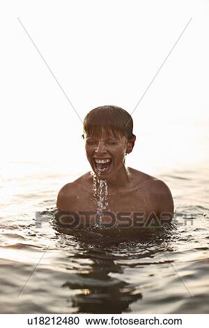 Teenage boy playing in water View Large Photo Image Stock Image - Teenage boy playing in water. Fotosearch