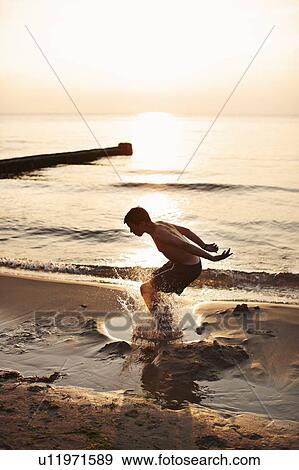 Teenage boy playing in water View Large Photo Image Stock Photo - Teenage boy playing in water. Fotosearch