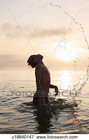 Teenage boy playing in water View Large Photo Image Stock Photo - Teenage boy playing in water. Fotosearch