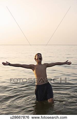 Stock Photograph - Teenage boy playing in water. Fotosearch