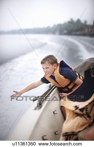 Teenage boy reaching to water from boat View Large Photo Image Stock Image - Teenage boy reaching to water from boat. Fotosearch