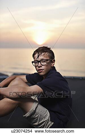 Picture - Teenage boy sitting on trampoline. Fotosearch