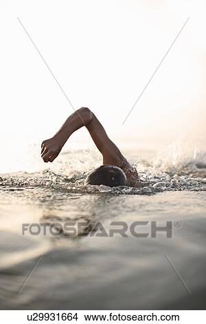 Picture - Teenage boy swimming in water. Fotosearch