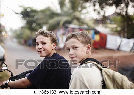 Teenage boys riding scooter on dirt road View Large Photo Image Stock Image - Teenage boys riding scooter on dirt road. Fotosearch