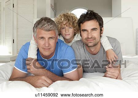 Stock Image - Three generations of men on bed. Fotosearch