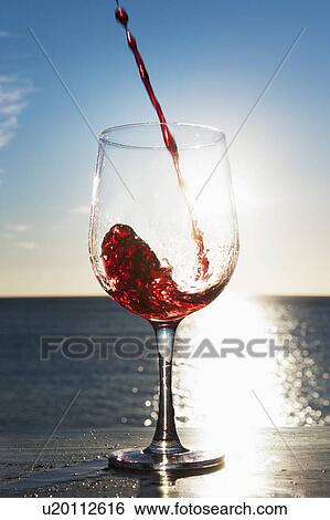 Stock Photograph - Wine pouring into glass outdoors. Fotosearch
