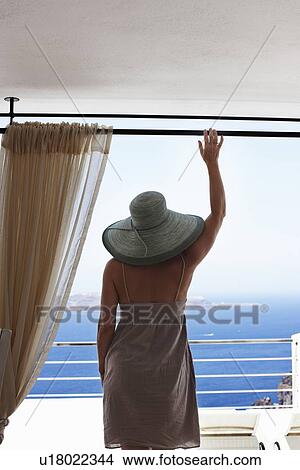 Picture - Woman admiring ocean view from balcony. Fotosearch
