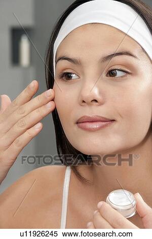 Woman applying moisturizer in mirror View Large Photo Image Stock Photography - Woman applying moisturizer in mirror. Fotosearch