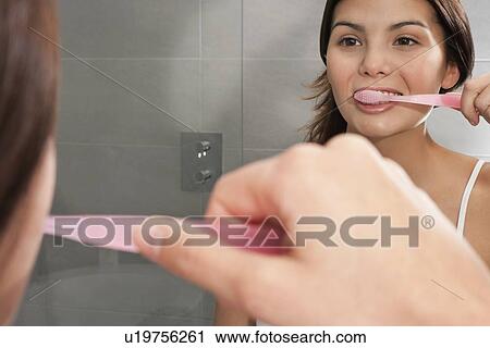 Woman brushing her teeth in mirror View Large Photo Image Stock Image - Woman brushing her teeth in mirror. Fotosearch