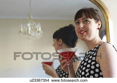 Picture - Woman drinking cocktail by mirror. Fotosearch