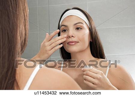 Woman examining her face in mirror View Large Photo Image Stock Image - Woman examining her face in mirror. Fotosearch