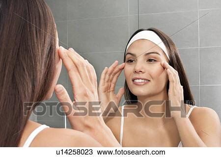 Woman examining her face in mirror View Large Photo Image Stock Image - Woman examining her face in mirror. Fotosearch