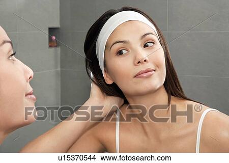 Woman examining her hair in mirror View Large Photo Image Picture - Woman examining her hair in mirror. Fotosearch