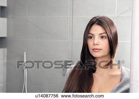 Stock Photograph - Woman examining herself in mirror. Fotosearch