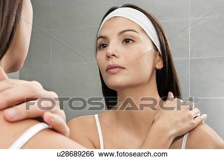 Stock Photograph - Woman examining herself in mirror. Fotosearch