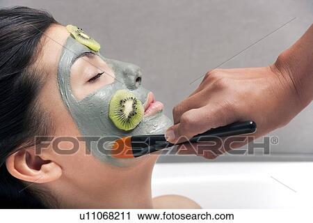 Stock Image - Woman having skin mask applied in bath. Fotosearch
