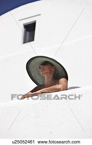 Woman in sunhat standing on balcony View Large Photo Image Stock Image - Woman in sunhat standing on balcony. Fotosearch