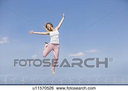 Woman jumping for joy over wind turbines View Large Photo Image Stock Photograph - Woman jumping for joy over wind turbines. Fotosearch