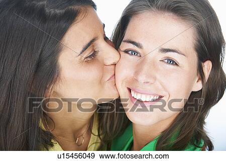 Woman kissing smiling friends cheek View Large Photo Image Stock Photo - Woman kissing smiling friends cheek. Fotosearch
