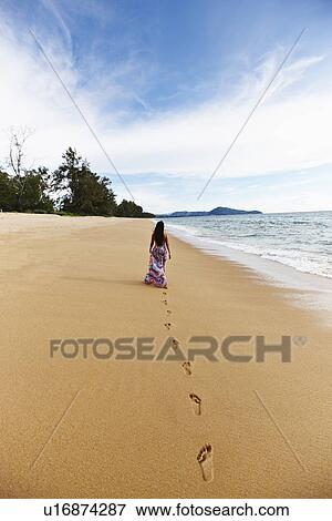 Stock Photo - Woman making footprints on sandy beach. Fotosearch