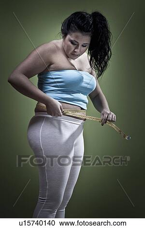 Stock Image - Woman measuring her waistline. Fotosearch