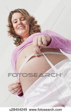Stock Photo - Woman measuring pregnant belly. Fotosearch