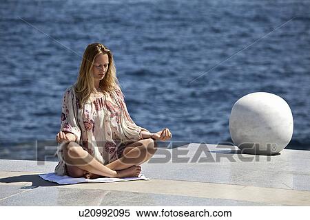 Stock Photography - Woman meditating on tiled surface. Fotosearch