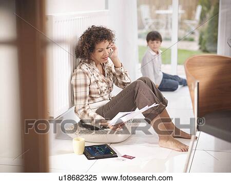 Stock Photography - Woman on cell phone against radiator. Fotosearch