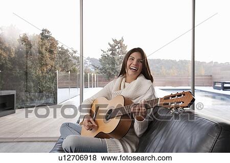 Woman playing guitar in living room View Large Photo Image Stock Photo - Woman playing guitar in living room. Fotosearch