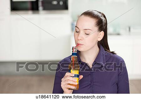 Stock Image - Woman sipping from bottle with straw. Fotosearch