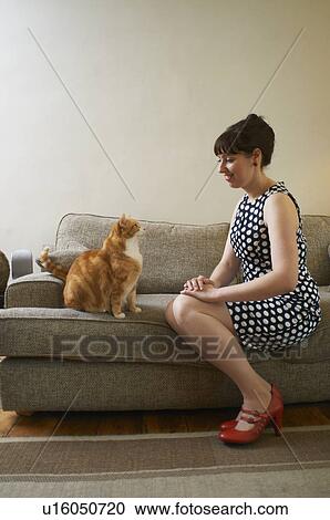 Stock Image - Woman sitting with cat on sofa. Fotosearch