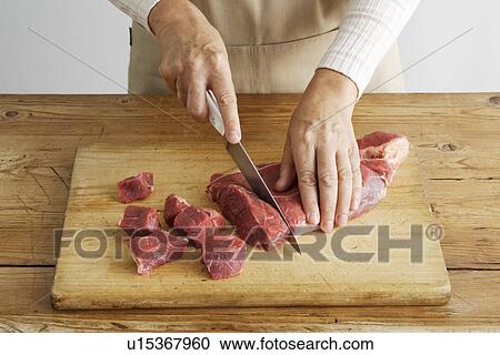 Woman slicing meat on wooden board View Large Photo Image Stock Image - Woman slicing meat on wooden board. Fotosearch