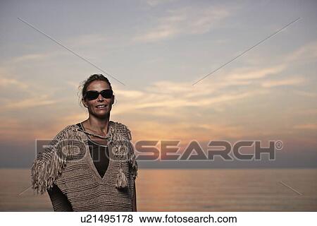 Woman standing on beach at sunset View Large Photo Image Stock Photo - Woman standing on beach at sunset. Fotosearch