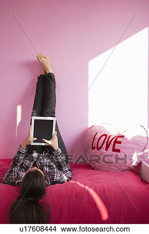 Woman using tablet computer on bed View Large Photo Image Picture - Woman using tablet computer on bed. Fotosearch