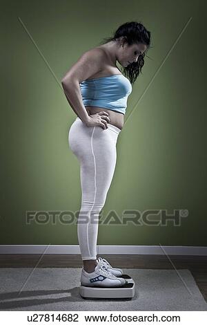 Woman weighing herself on scale View Large Photo Image Stock Image - Woman weighing herself on scale. Fotosearch