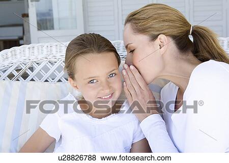 Woman whispering to smiling daughter View Large Photo Image Stock Photo - Woman whispering to smiling daughter. Fotosearch