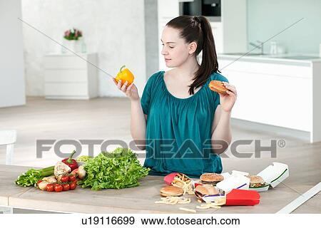 Woman with fast food and vegetables View Large Photo Image Stock Photo - Woman with fast food and vegetables. Fotosearch