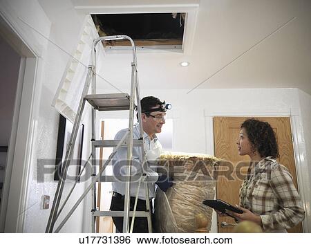 Stock Photograph - Worker carrying insulation to attic. Fotosearch