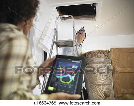 Stock Photography - Worker carrying insulation to attic. Fotosearch