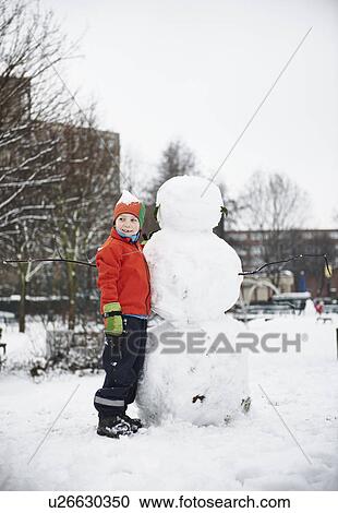 Boy building snowman in park View Large Photo Image Stock Image - Boy building snowman in park. Fotosearch