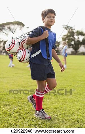 Boy carrying soccer balls on pitch View Large Photo Image Stock Photograph - Boy carrying soccer balls on pitch. Fotosearch