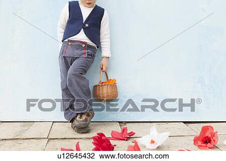 Stock Image - Boy holding basket of paper flowers. Fotosearch