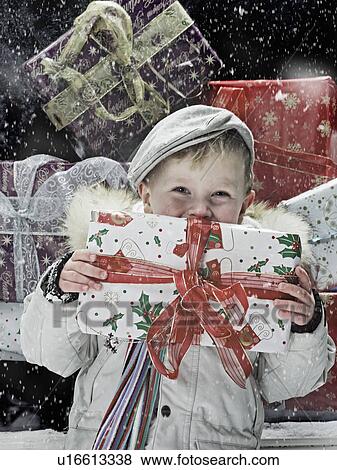 Boy holding Christmas present in snow View Large Photo Image Stock Photo - Boy holding Christmas present in snow. Fotosearch