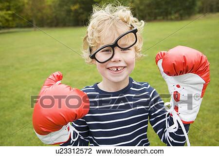Stock Image - Boy playing with boxing gloves outdoors. Fotosearch