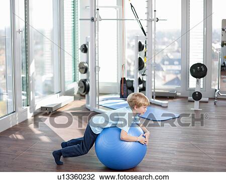 Stock Image - Boy playing with exercise ball in gym. Fotosearch
