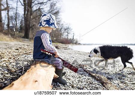 Stock Photo - Boy playing with guitar on log. Fotosearch