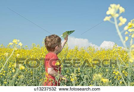 Boy playing with paper airplane in field View Large Photo Image Stock Image - Boy playing with paper airplane in field. Fotosearch