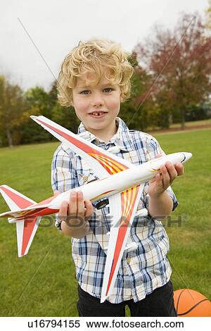 Stock Photography - Boy playing with toy airplane outdoors. Fotosearch