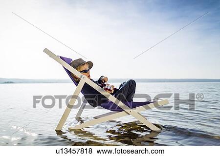 Stock Photo - Boy relaxing in lawn chair in creek. Fotosearch
